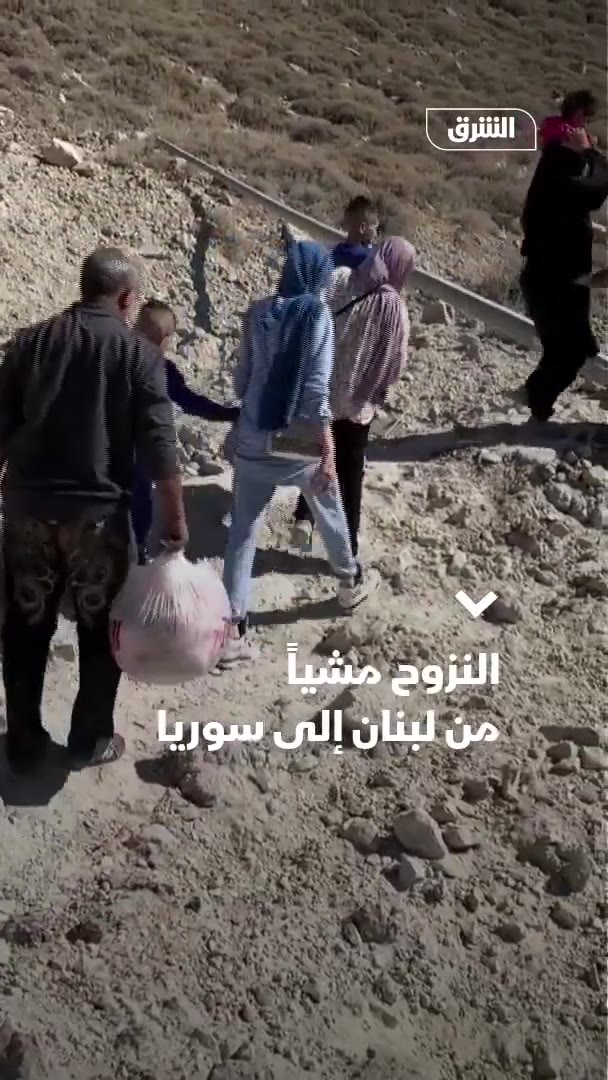 Displaced people from Lebanon head to the Al-Masnaa border crossing with Syria on foot after an Israeli raid cut off the road leading to it