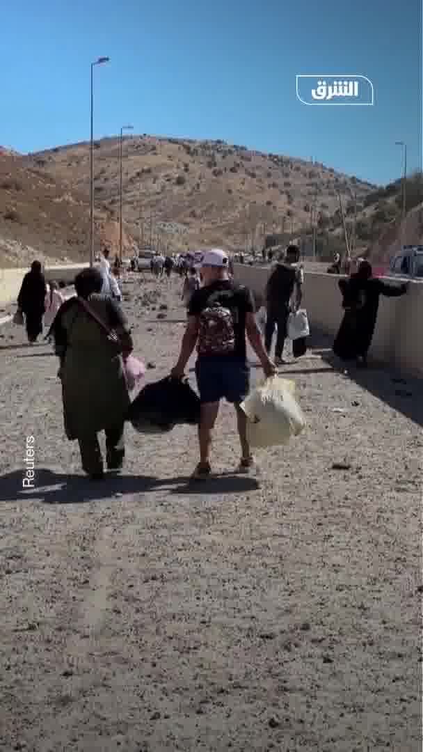 Displaced people from Lebanon head to the Al-Masnaa border crossing with Syria on foot after an Israeli raid cut off the road leading to it