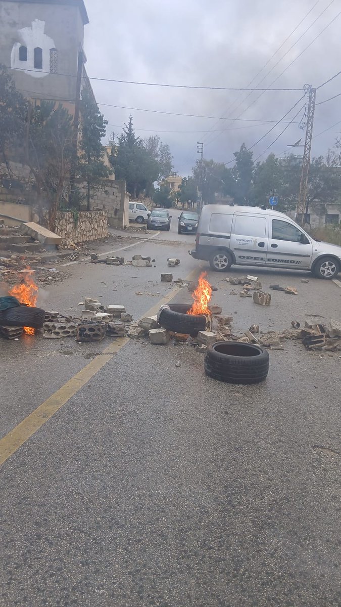 A citizen blocks the road between Taybeh and Deir Siryan with burning tires in protest against the lack of compensation after his house was damaged in recent Israeli airstrikes on the area.